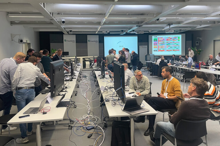 Entwickler beim DTVP Plugfest 2025 in einem modernen Konferenzraum, geschäftlich am Austausch.