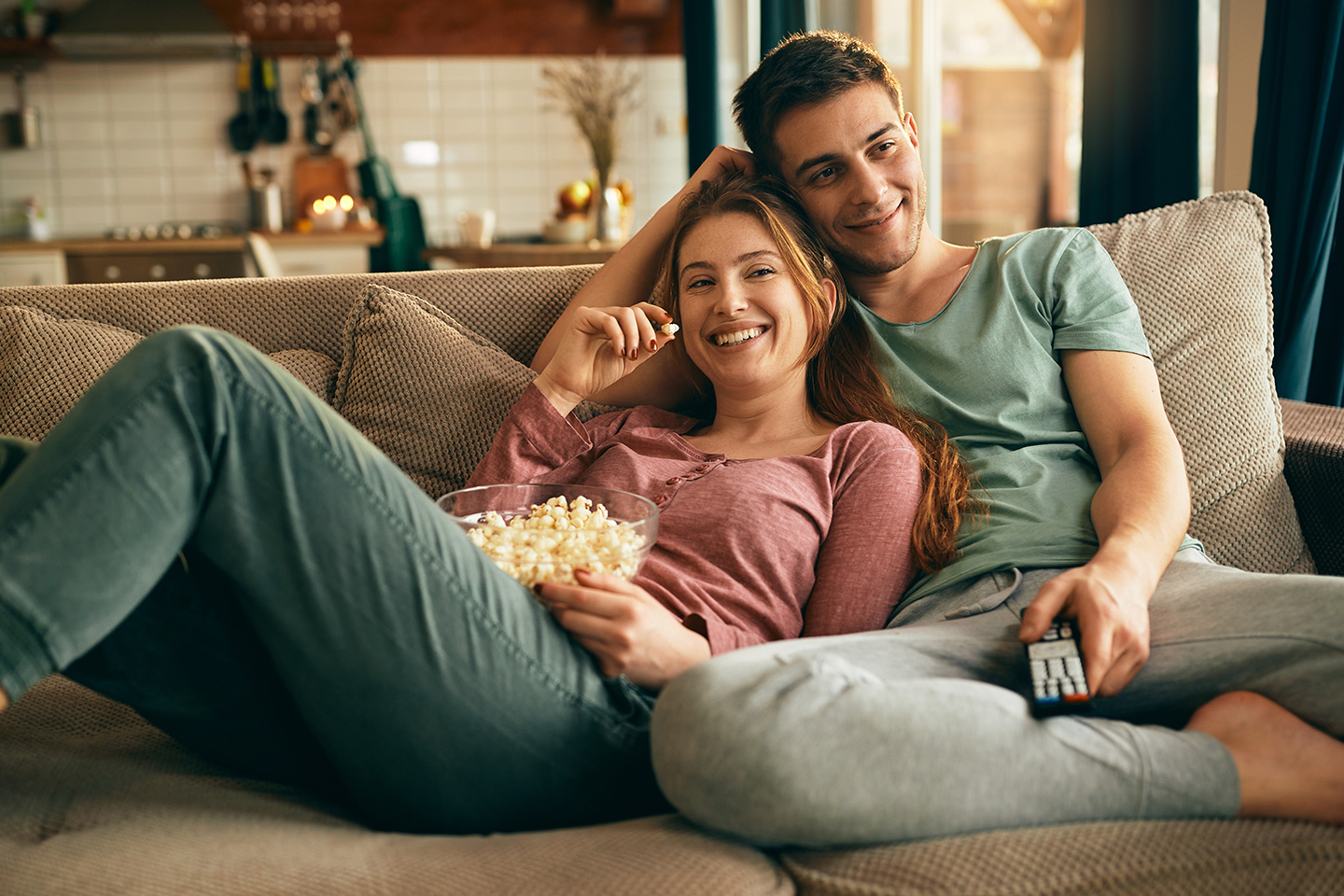 Junges Paar gemütlich liegend auf der Couch beim Fernsehschauen