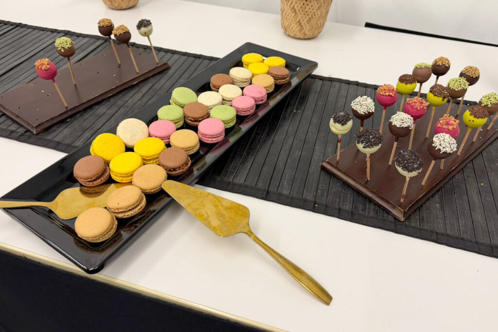 Bunte Macarons auf schwarzem Teller und Schokoladen-Cakepops auf Stielen als Dessert-Buffet bei Plugfest Berlin